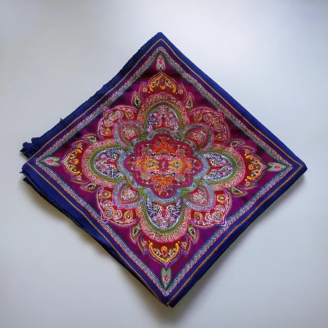 Bandana cuadrada de algodón con diseño paisley en primer plano, popular como accesorio de moda.