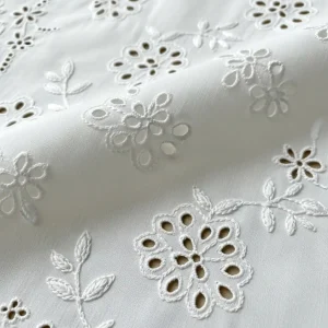 Detalle de Bordado Inglés sobre tela de batista de algodón blanca, con calados florales y puntadas de ojal. Técnica de bordado whitework.