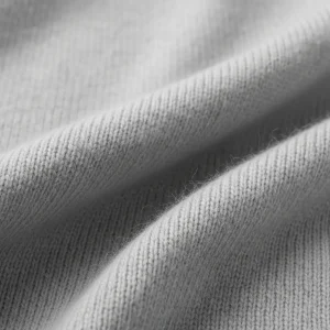 Macro de tejido de punto de cachemira pura color gris perla, mostrando su textura extremadamente suave, fina y ligera. Fibra de lujo para jerséis y bufandas.