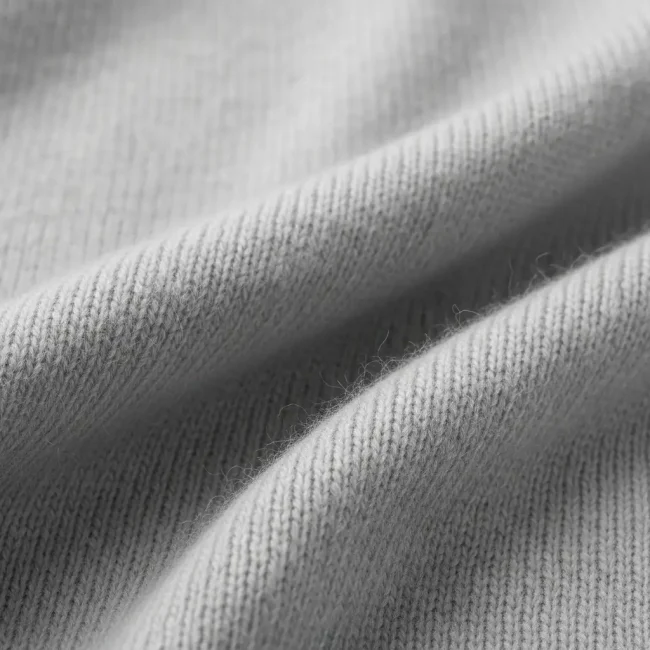 Macro de tejido de punto de cachemira pura color gris perla, mostrando su textura extremadamente suave, fina y ligera. Fibra de lujo para jerséis y bufandas.