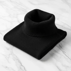 Suéter de cuello de tortuga negro de lana merina fina, doblado, mostrando su cuello alto y ajustado. Prenda clásica para el frío.