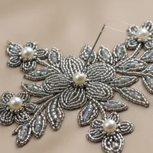 Bordado con cuentas, perlas y canutillos sobre satén de seda, mostrando un diseño floral. Adorno de lujo para alta costura.