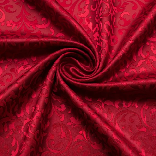 Macro de tela de Damasco de seda color rojo rubí, con patrones de arabescos brillantes sobre fondo mate. Tejido reversible de lujo.