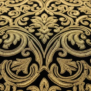 Bordado de damasquinado con hilo de oro sobre terciopelo negro, mostrando un patrón de arabescos en relieve. Técnica de ornamentación de lujo.