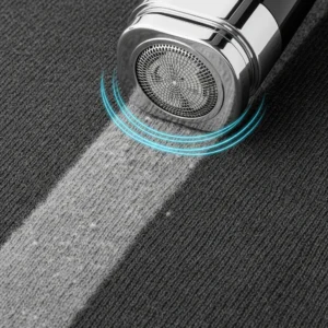 Máquina quitapelusas eléctrica realizando el despeluzado de un jersey de lana gris con pilling. Proceso de eliminación de pelusa y bolitas.