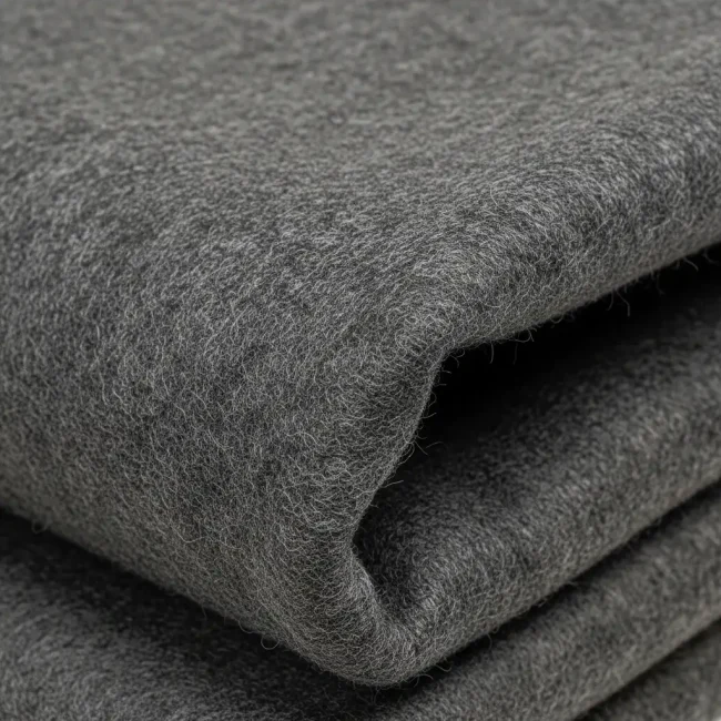 Macro de tejido burel de lana color gris antracita, mostrando su textura densa, afieltrada y resistente. Tela tradicional portuguesa para abrigos.