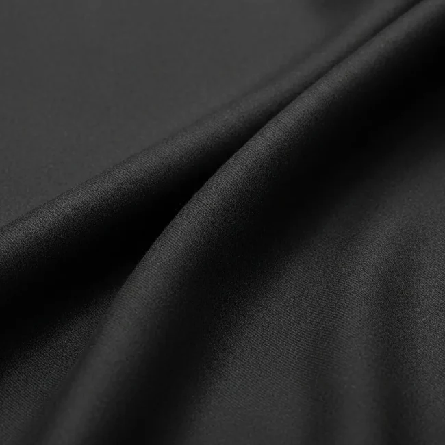 Macro de tejido Casimir de lana peinada fina color gris marengo, mostrando su superficie lisa y lustre sutil. Tela de alta calidad para trajes.