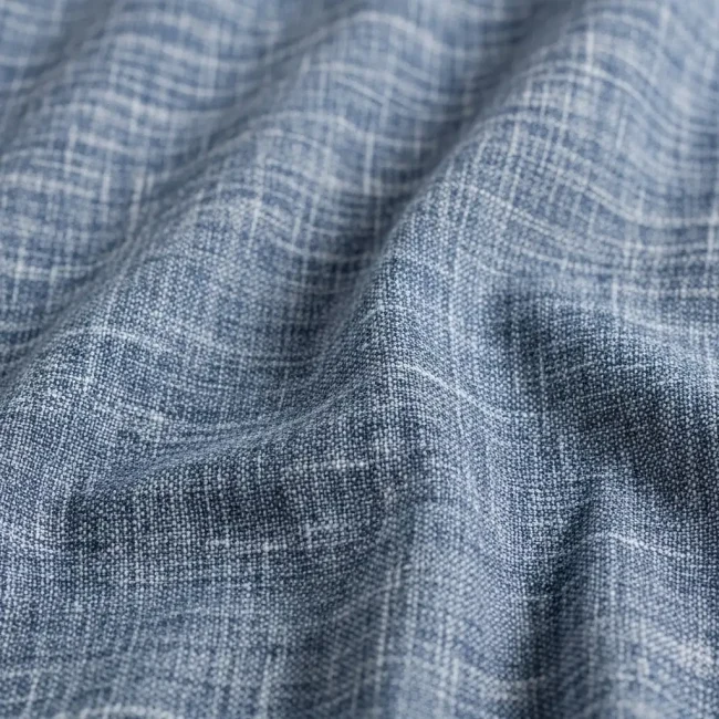 Macro de tejido chambray de algodón azul, mostrando su efecto de color jaspeado y textura suave. Tela ligera para camisas y vestidos.