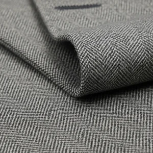 Macro de tejido Cheviot de lana con patrón de espiga en tonos grises. Tela resistente y duradera para trajes y abrigos.