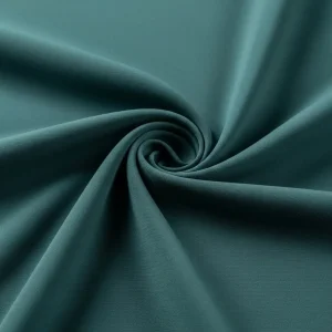 Macro de tejido crespón de seda color verde azulado, mostrando su superficie rugosa y su caída fluida. Tela elegante para vestidos y blusas.