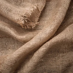 Primer plano de una tela de arpillera mostrando su textura áspera y tejida, típica de su uso en aplicaciones industriales y decorativas.