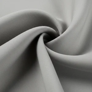 Tejido Dalia de lana fina color gris perla, mostrando su textura suave y caída elegante. Tela de alta calidad para trajes y abrigos.