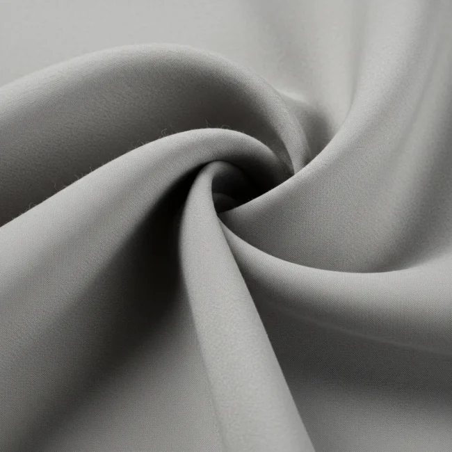 Tejido Dalia de lana fina color gris perla, mostrando su textura suave y caída elegante. Tela de alta calidad para trajes y abrigos.