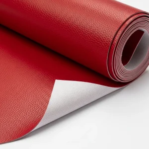 Rollo de cuero sintético (polipiel) de color rojo, mostrando su textura granulada y su base textil. Alternativa vegana al cuero para moda y tapicería.