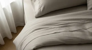 Cama hecha con algunos de los mejores materiales para sábanas, como bambú y lino, mostrando texturas ideales para un descanso perfecto.