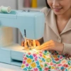 Persona sonriendo mientras aprende a usar una máquina de coser con tela colorida, superando el miedo inicial.